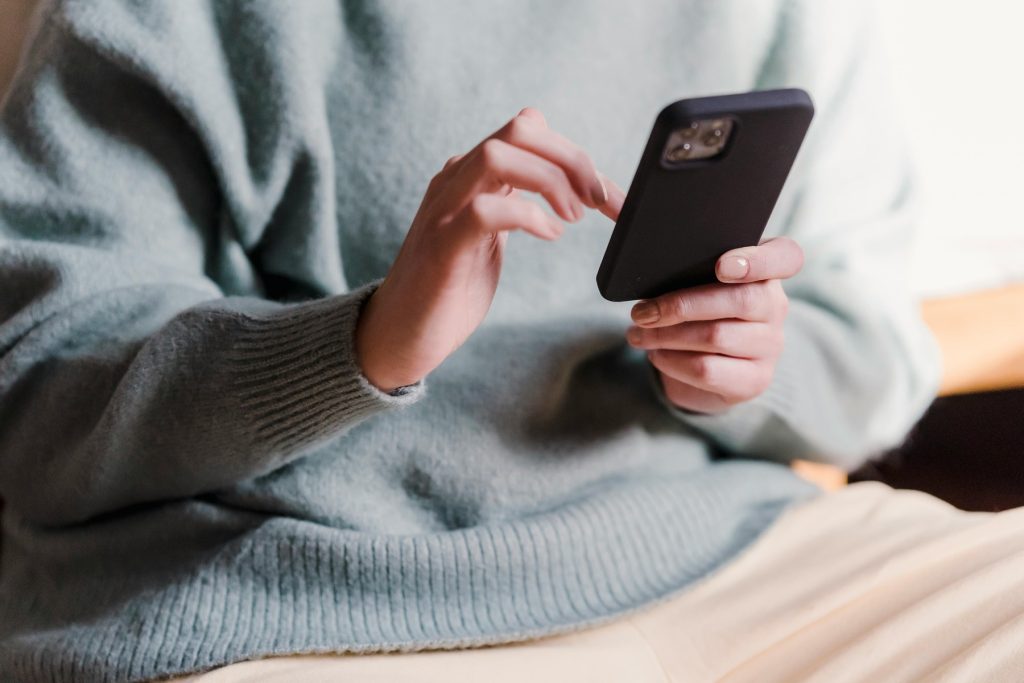A person wearing a light blue sweater using a smartphone, representing digital convenience