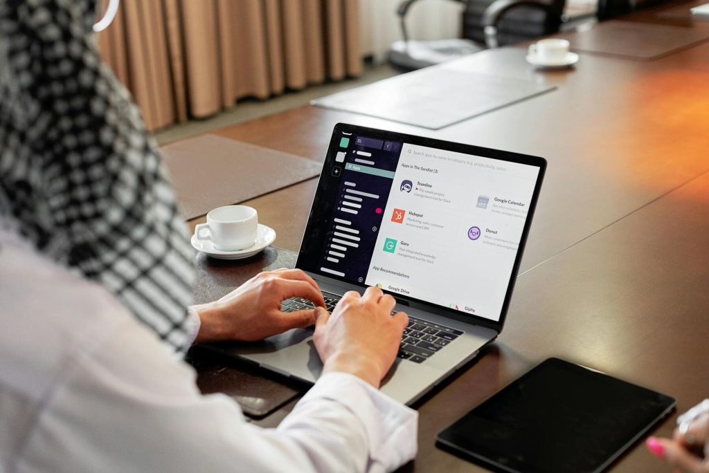 A man in a white shirt is focused on using a laptop