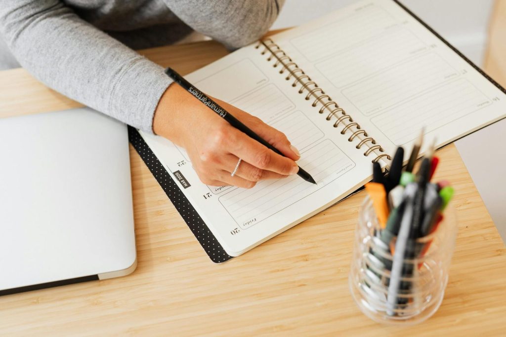 A woman is engaged in writing in a notebook on a rustic wooden desk