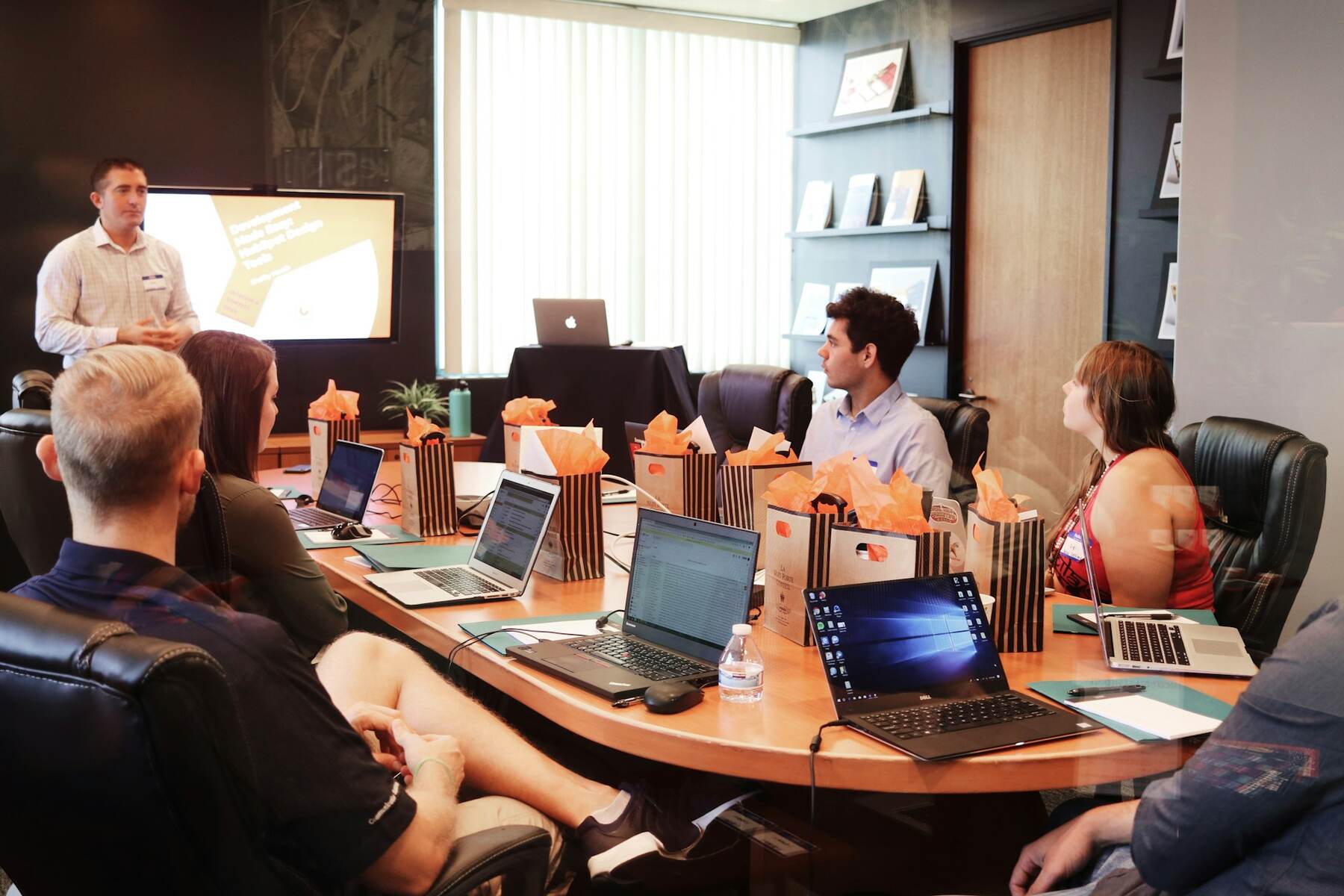 A team of professionals around a table, each with a laptop, collaborating and exchanging thoughts in a work setting