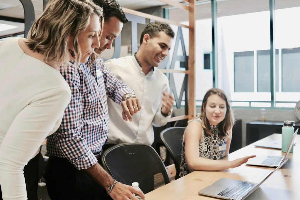 Team collaborating on a laptop, reviewing work at a meeting table in an office
