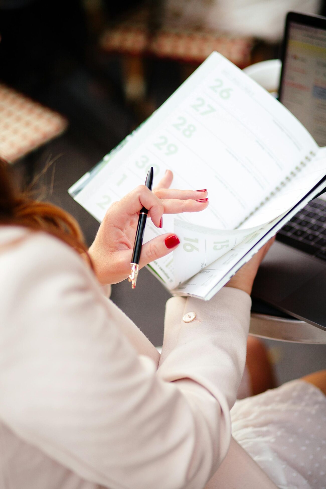 A person flipping through a calendar while holding a pen, reviewing their schedule