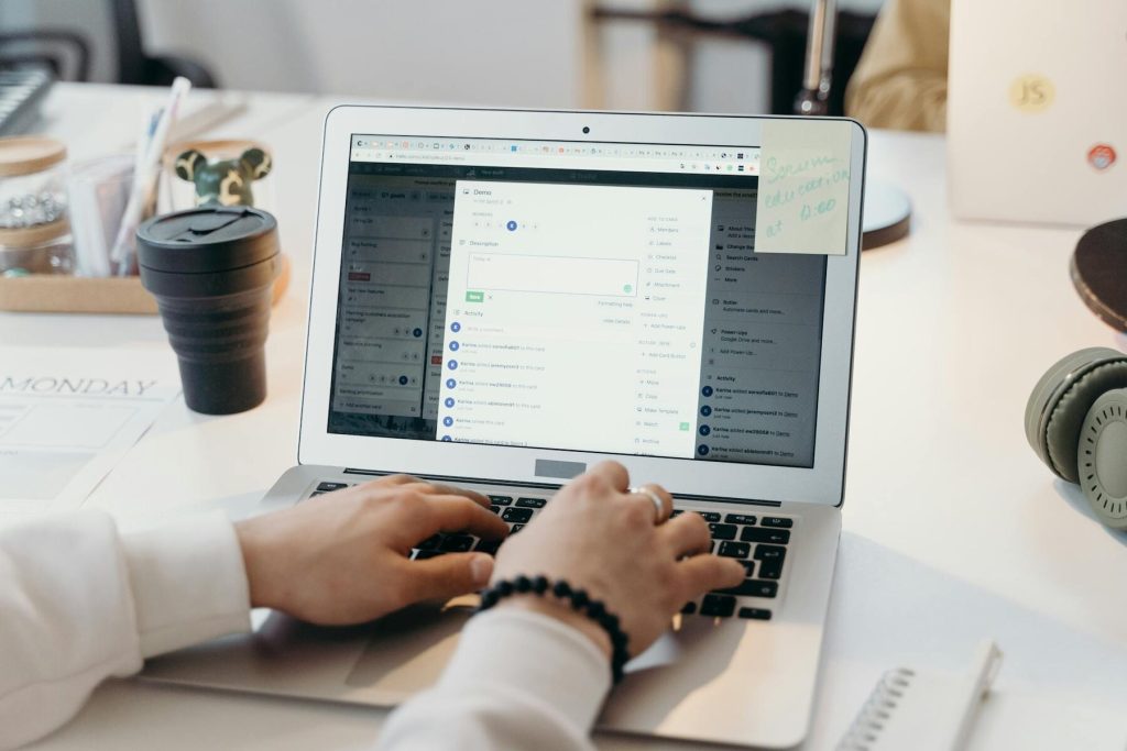 A close-up of hands typing on a laptop keyboard with a calendar and a cup visible on the desk